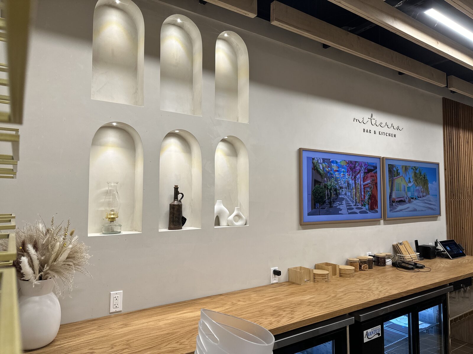 Framed art-mode displays and the restaurant's mark above the back counter