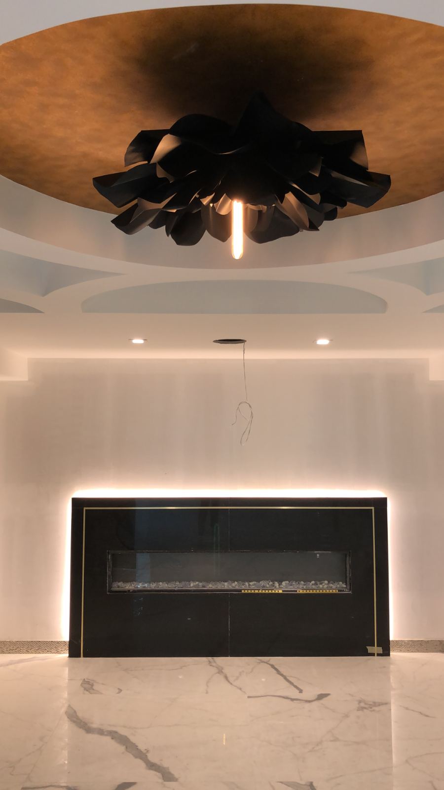 Cove lighting washing a fireplace wall and its ceiling detail