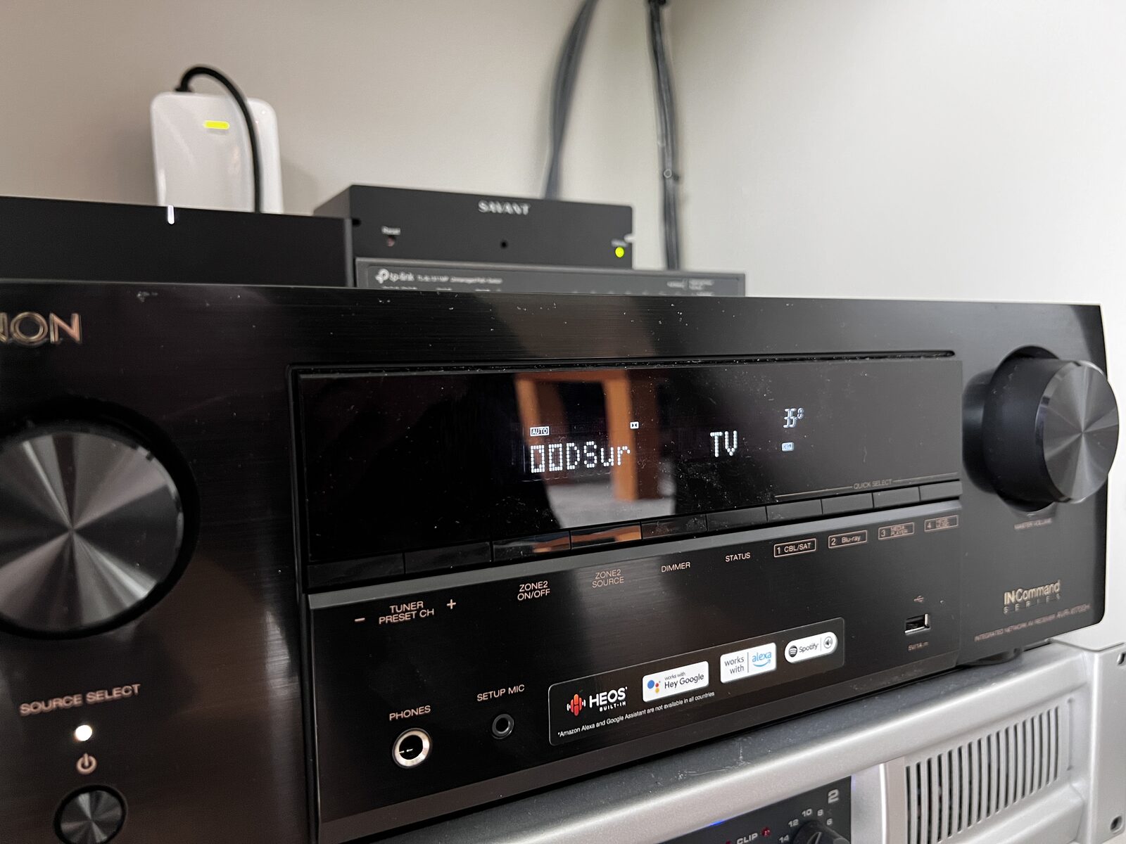 The receiver driving the room, racked below the display