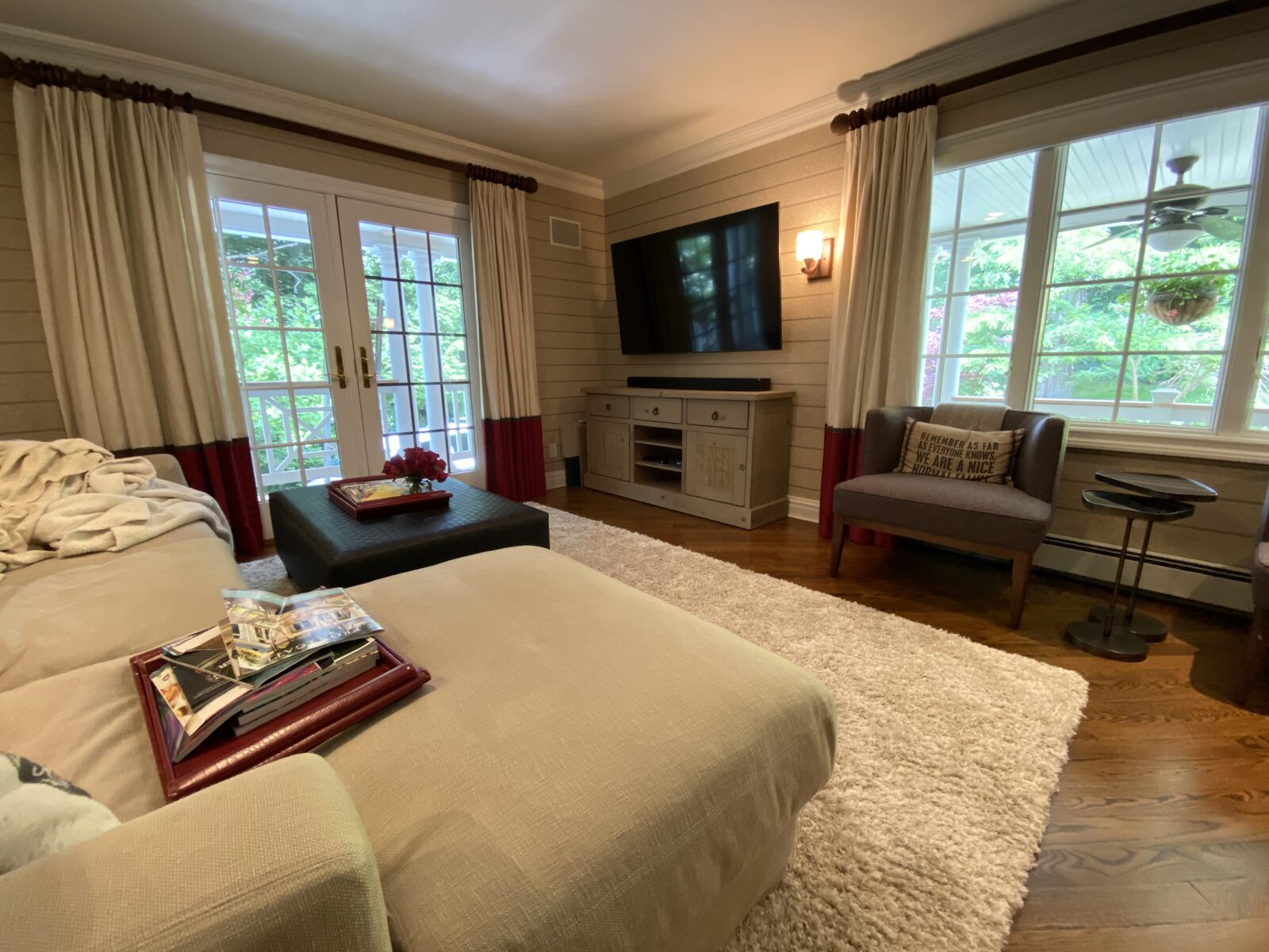 A living room with a wall-mounted display between two windows