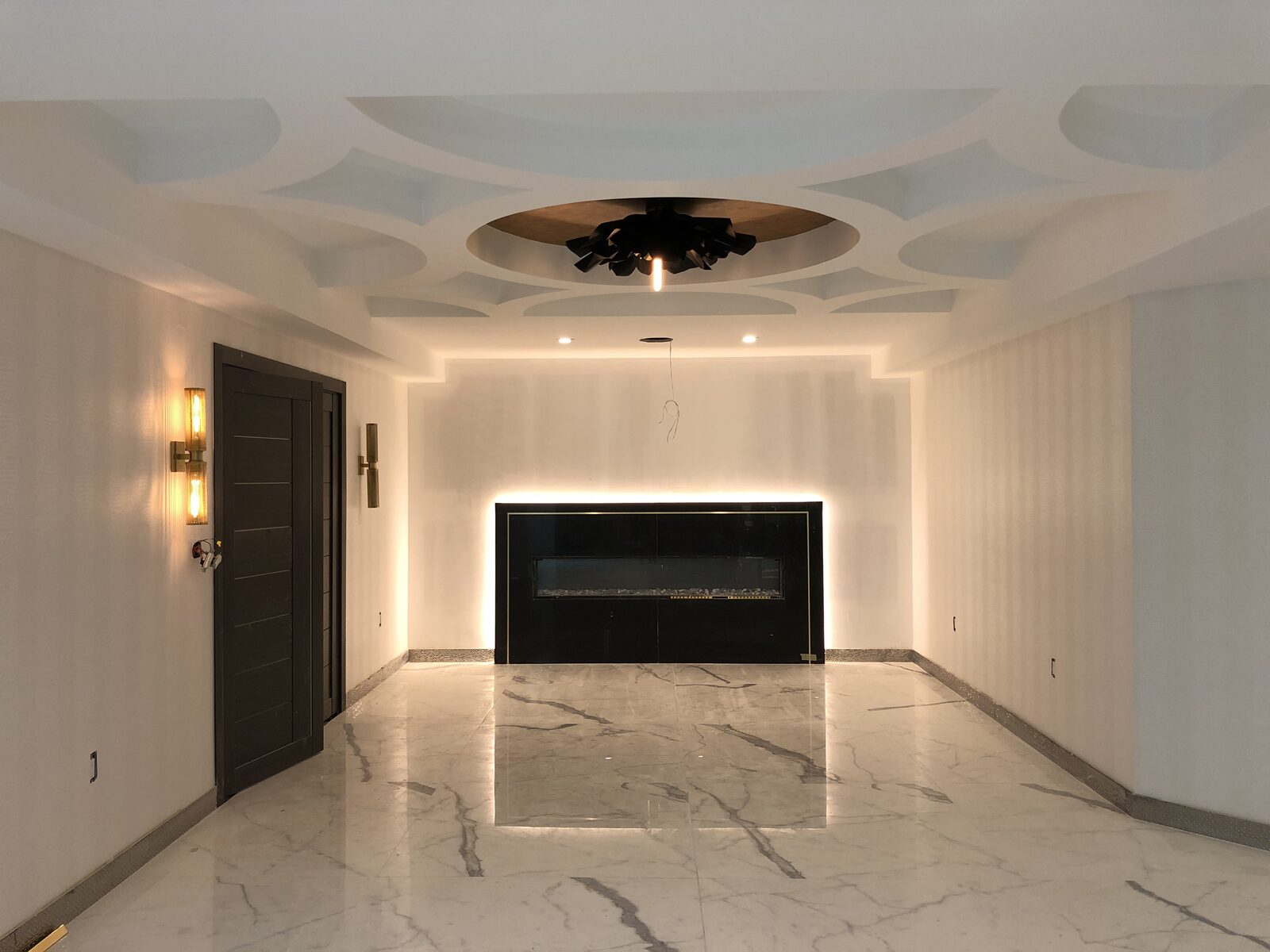 A hallway and fireplace lit by concealed cove lighting